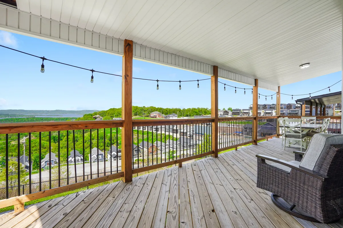 A cozy deck or patio with wooden railing, outdoor furniture, and twinkling string lights, overlooking a scenic landscape. The atmosphere suggests tranquil evenings and relaxing gatherings after a day on the lake.