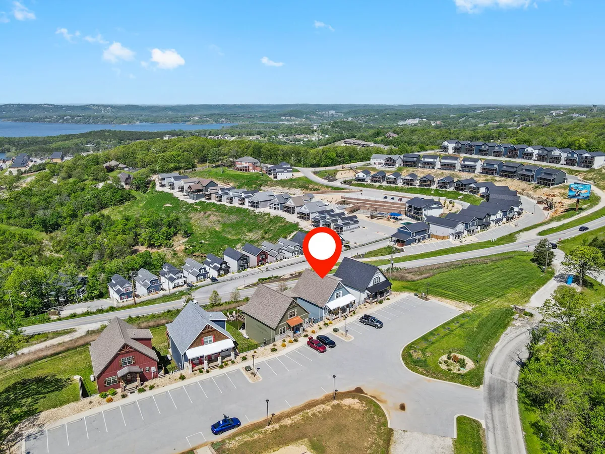This exterior image captures the neighborhood layout, featuring a nearby water body, parking area, and a mix of architectural styles. The vibrant outdoor scene conveys a sense of community and togetherness, with open spaces that invite outdoor gatherings and activities.