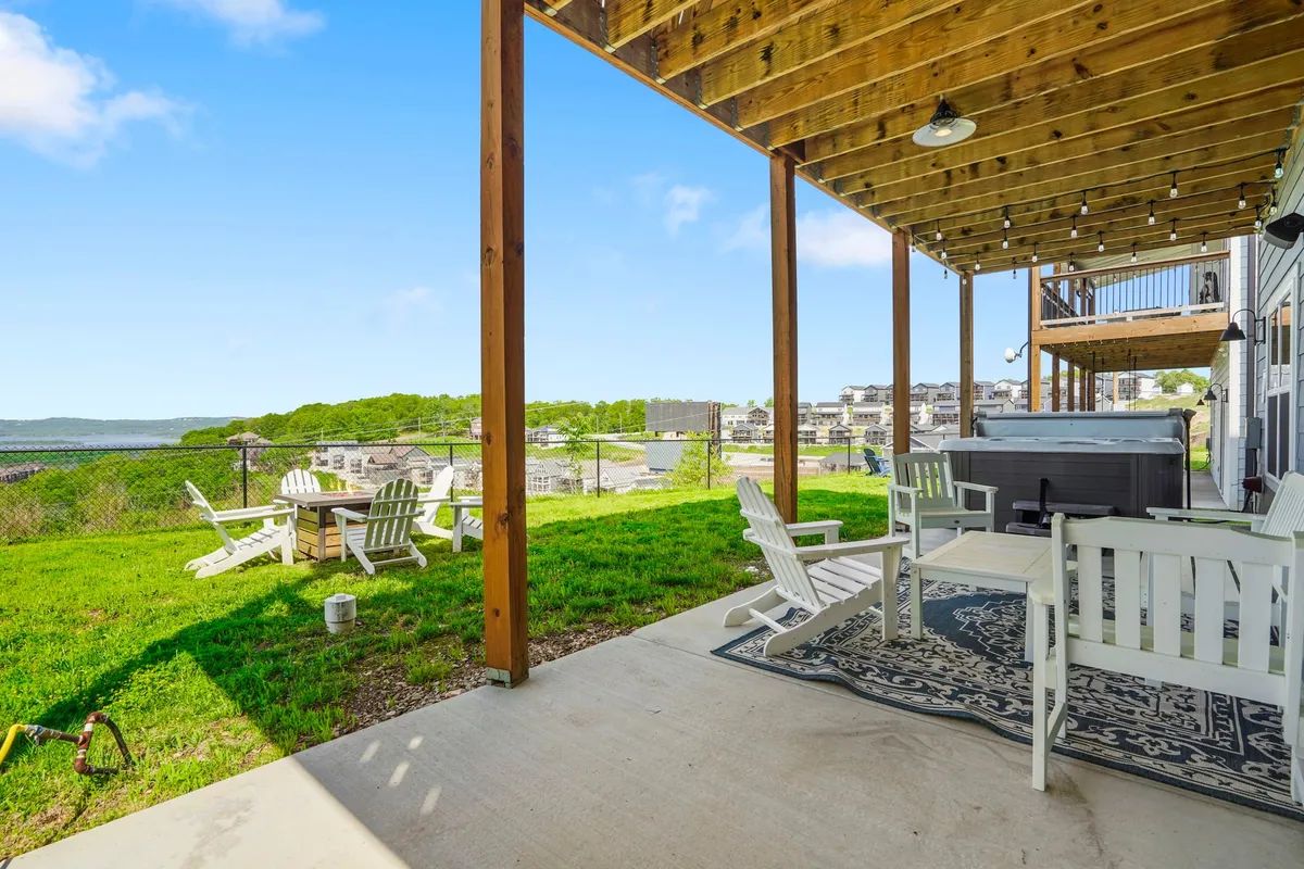 A patio outfitted with comfortable outdoor furniture, a bubbling hot tub, and a sweeping landscape view sets the scene. The image invites thoughts of evening relaxation, group conversation, and enjoying the outdoors together, all with a sense of privacy.