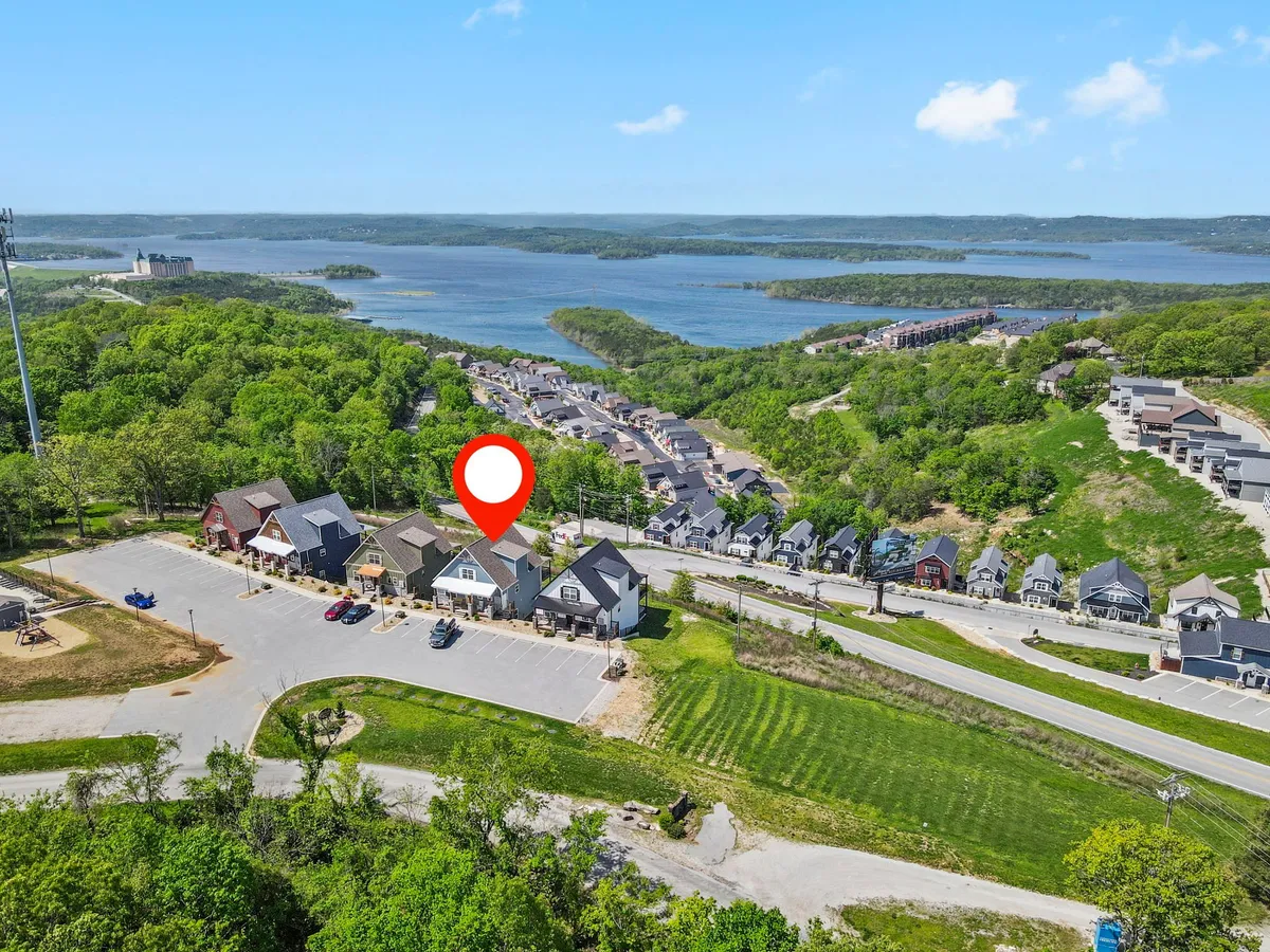 A scenic exterior image capturing a tranquil lake bordered by lush greenery and a quaint village. The road winds through the landscape, suggesting both serenity and opportunities for community exploration. The mood is tranquil, inviting guests to connect with the area.