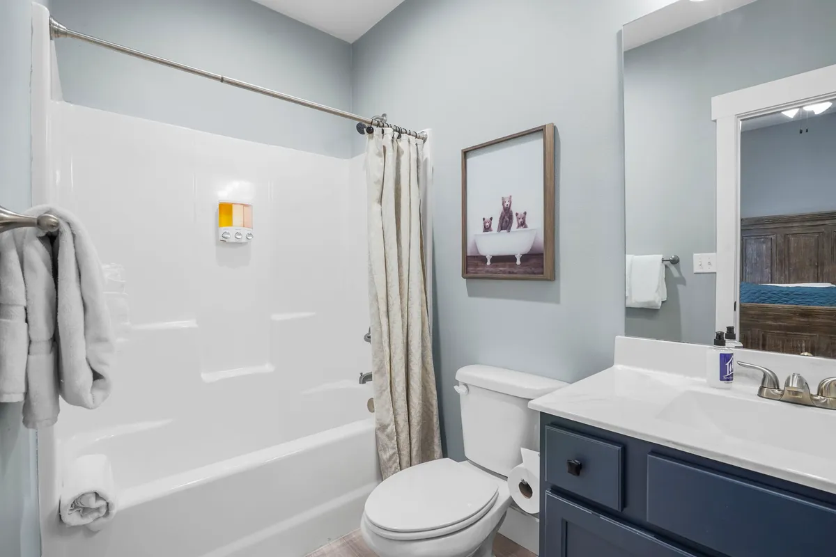 A bright ensuite bathroom with a vanity and sink, bathtub, framed artwork, and towel rack. The clean lines and elegant decor create a spa-like setting, ideal for a refreshing bath or quiet personal moments.