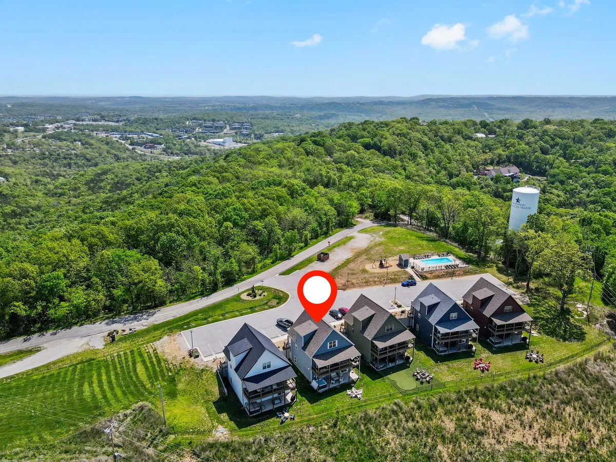 This image displays a cluster of charming houses nestled in green landscape, with a sparkling swimming pool and open community spaces visible. The setting feels relaxed and communal, emphasizing opportunities for outdoor gatherings, swimming, and enjoying nature within the exclusive mini-resort.